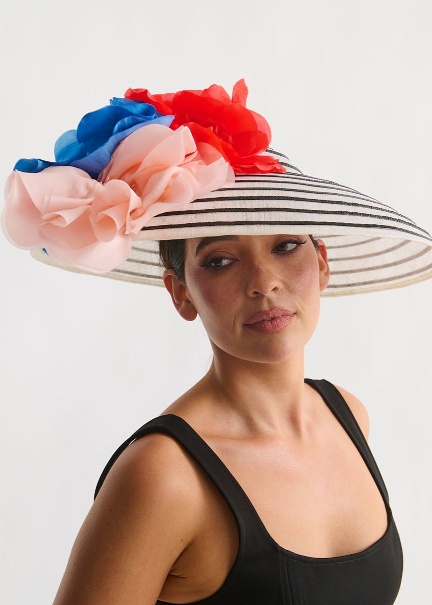 Woman wearing a decorative hat with red, blue, and pink flowers on a white background