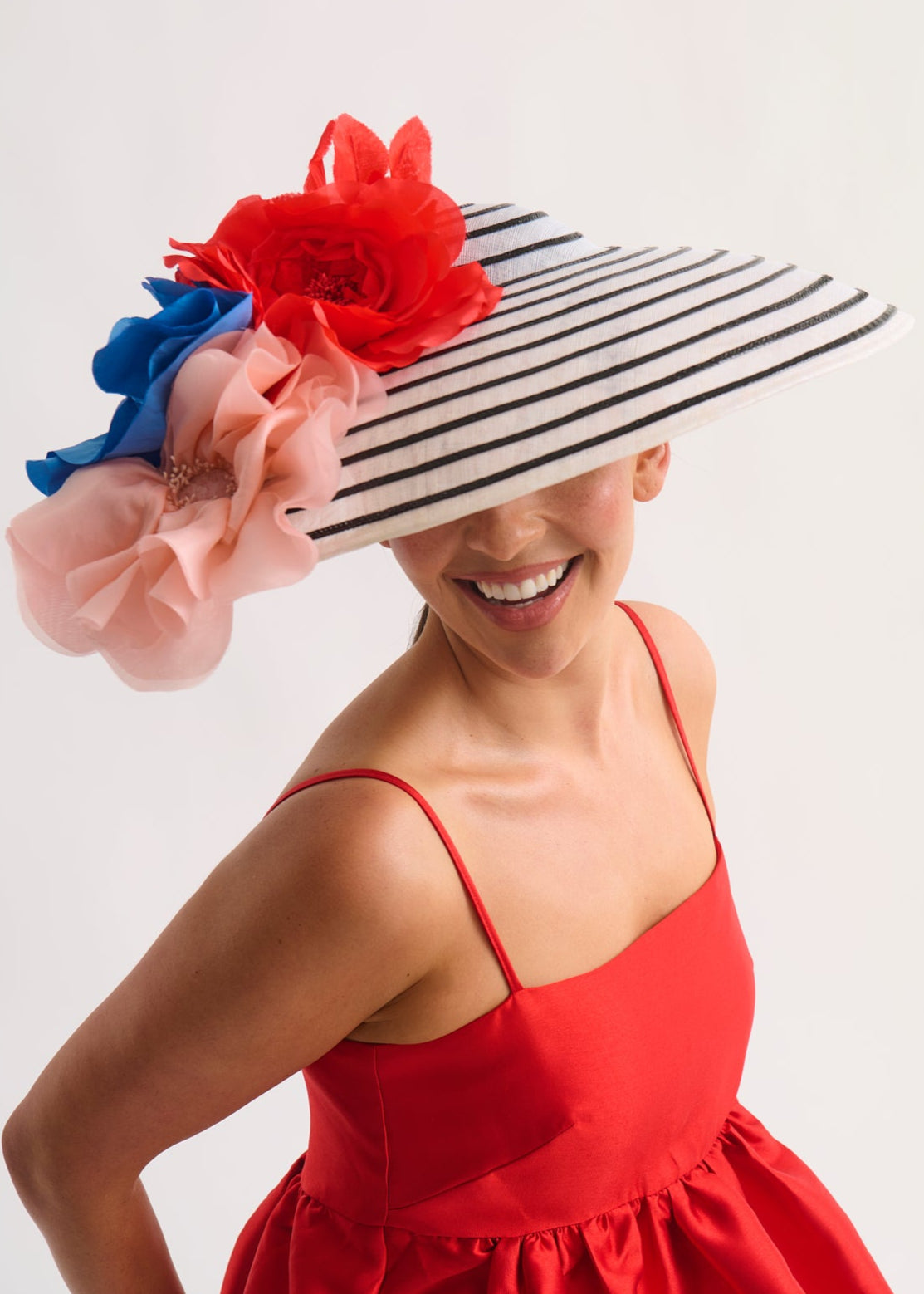 Woman wearing a decorative hat with red, blue, and pink flowers on a white background