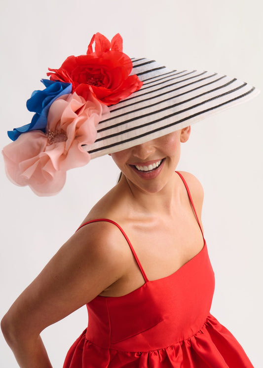 Woman wearing a decorative hat with red, blue, and pink flowers on a white background