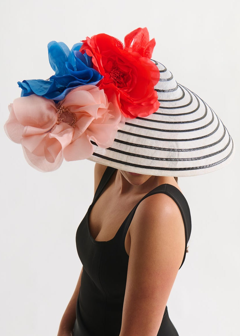 Person wearing a black dress and a decorative hat with flowers on a white background