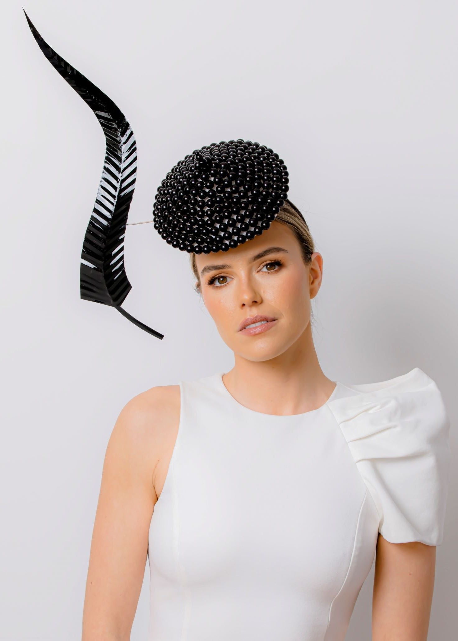 Woman wearing a black beaded hat with a white background