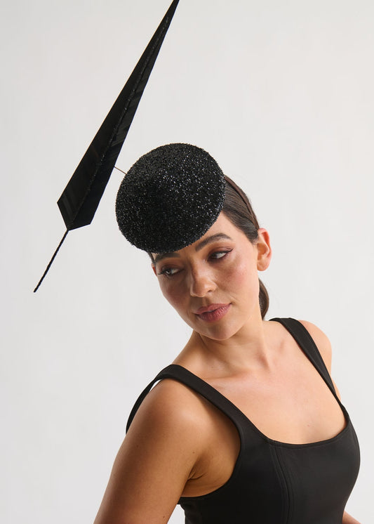 Woman wearing a black hat with a decorative element on a white background