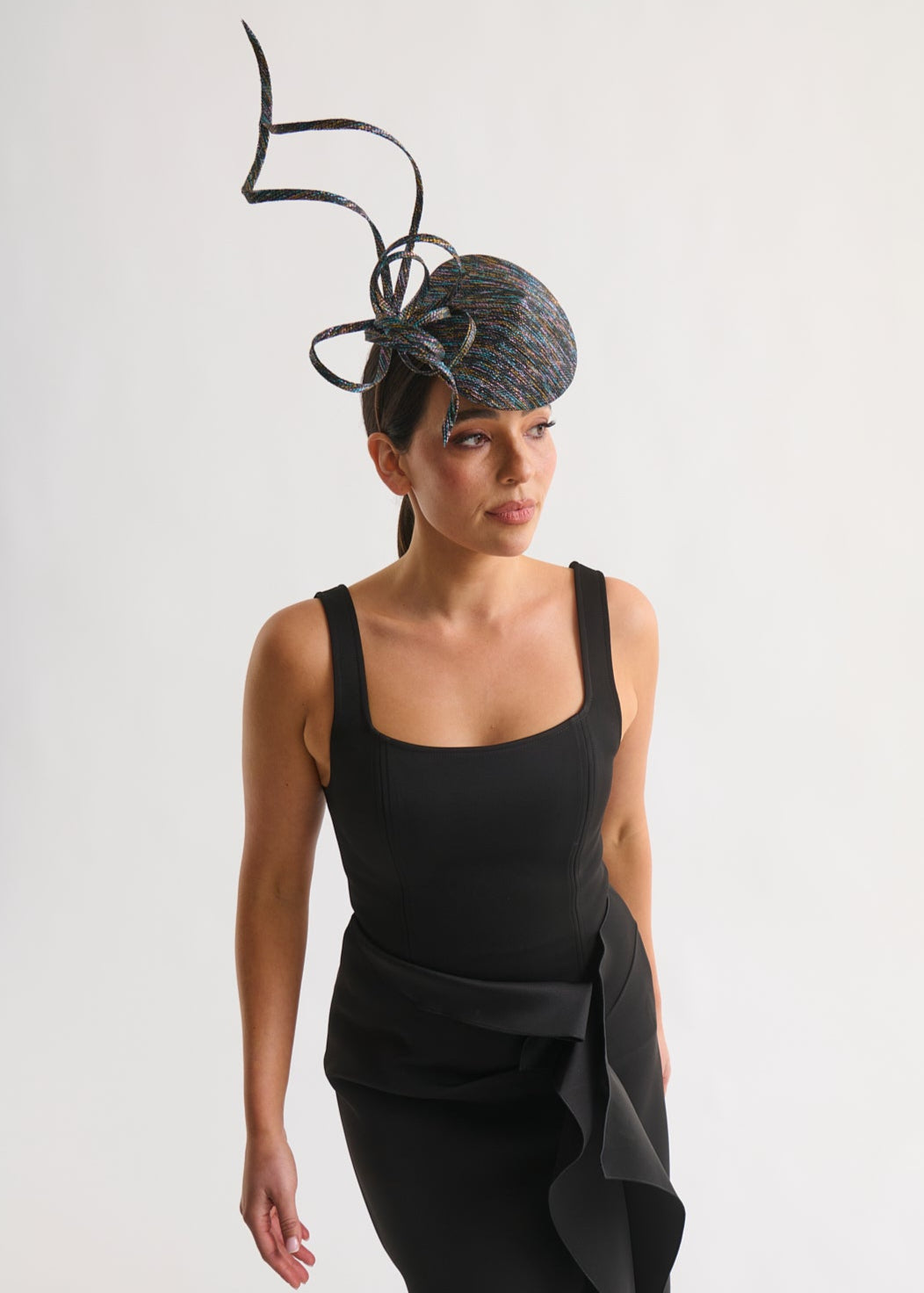 Woman wearing a black dress and decorative headpiece against a white background