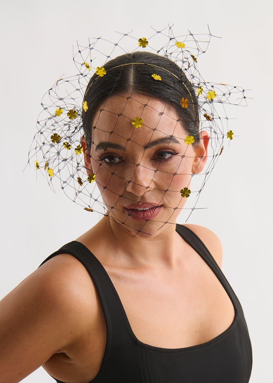 Woman wearing a black dress with a decorative headpiece veil against a white background