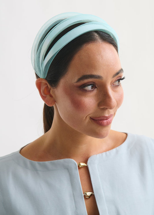 Woman wearing a light blue headband and dress against a plain background