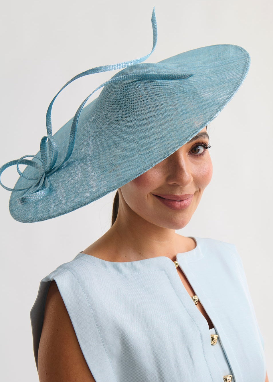 Woman wearing a light blue dress and matching hat against a white background