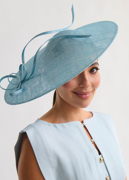 Woman wearing a light blue dress and matching hat against a white background