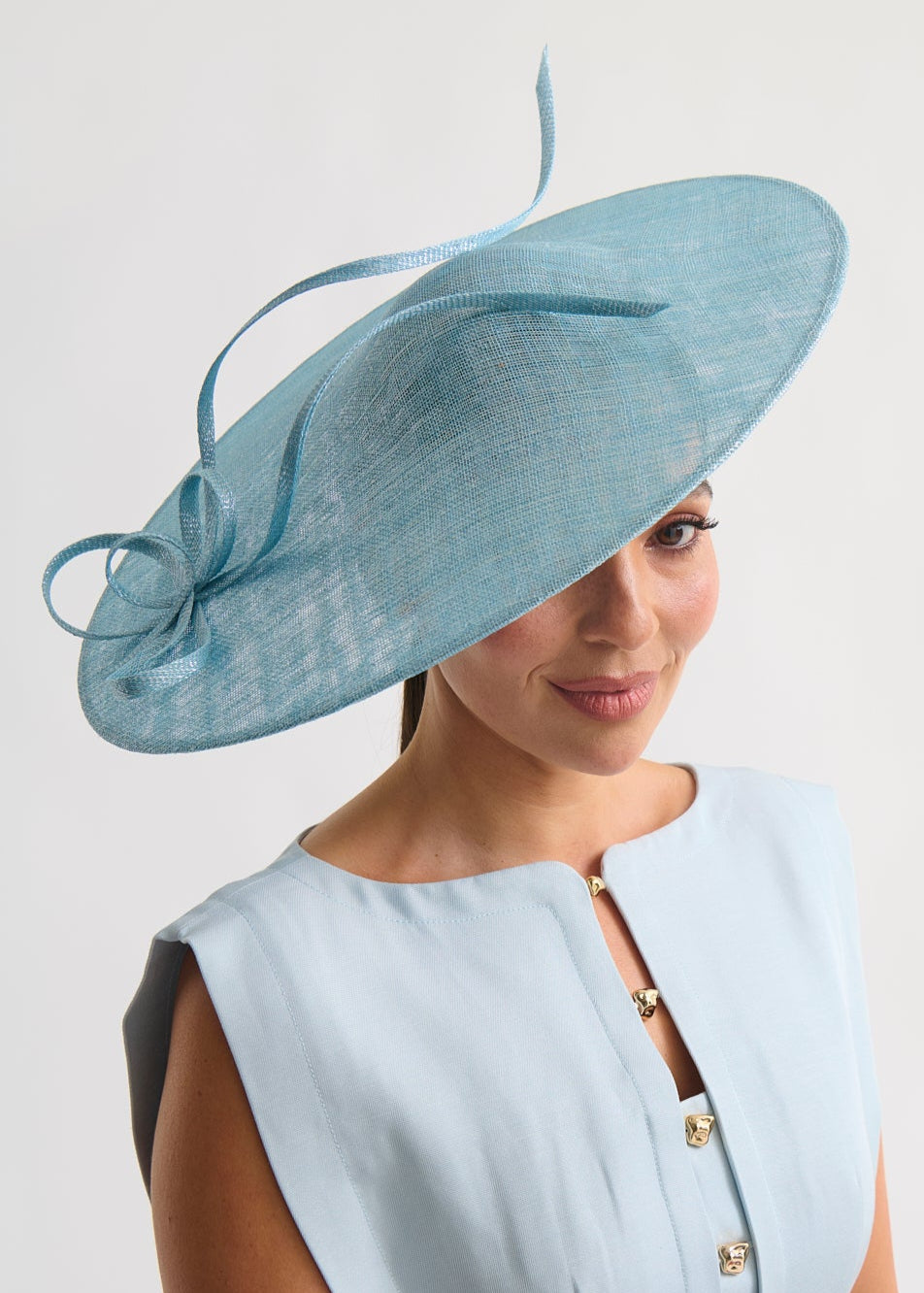 Woman wearing a light blue dress and matching hat against a white background