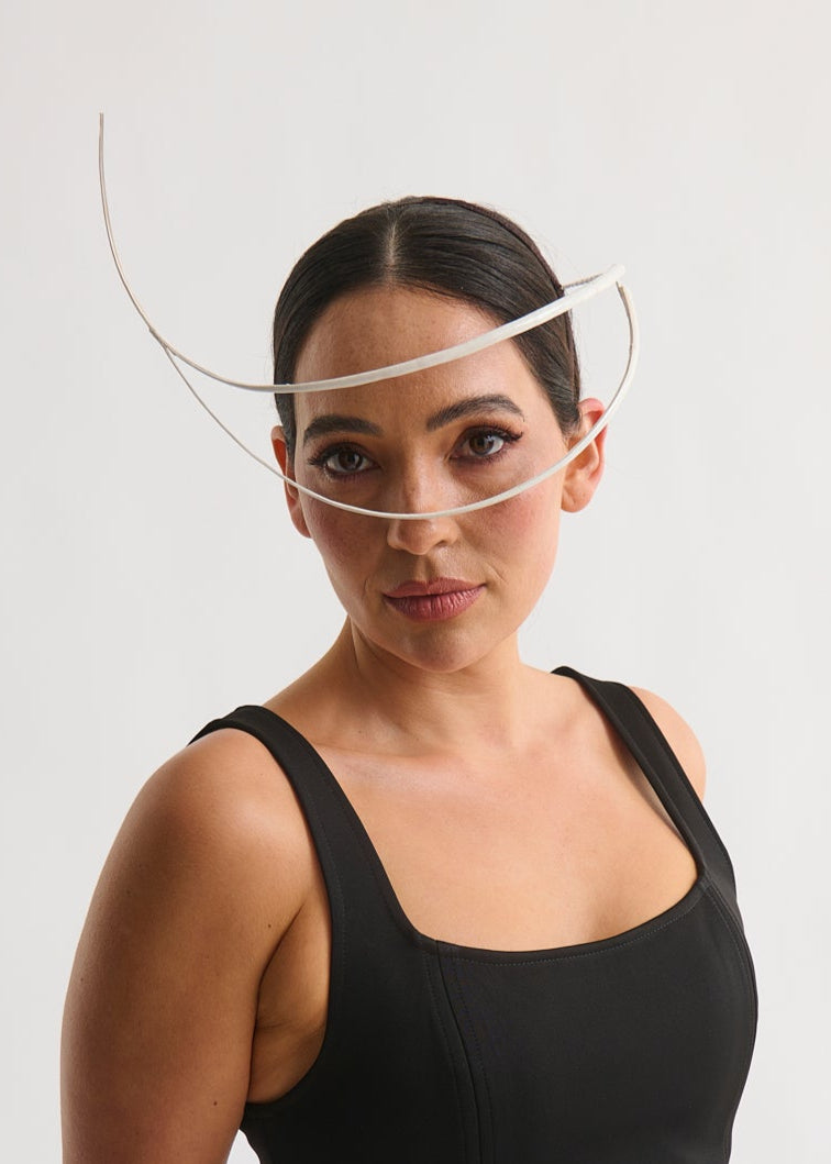Woman wearing a white feather quill headpiece and a black dress against a white background