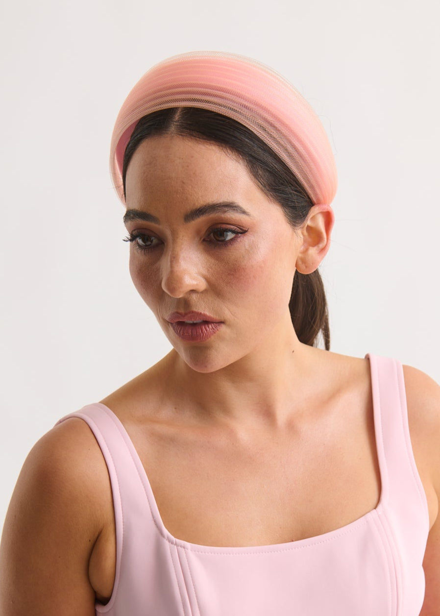 Woman wearing a pink dress and headband against a white background
