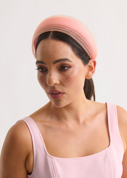 Woman wearing a pink dress and headband against a white background