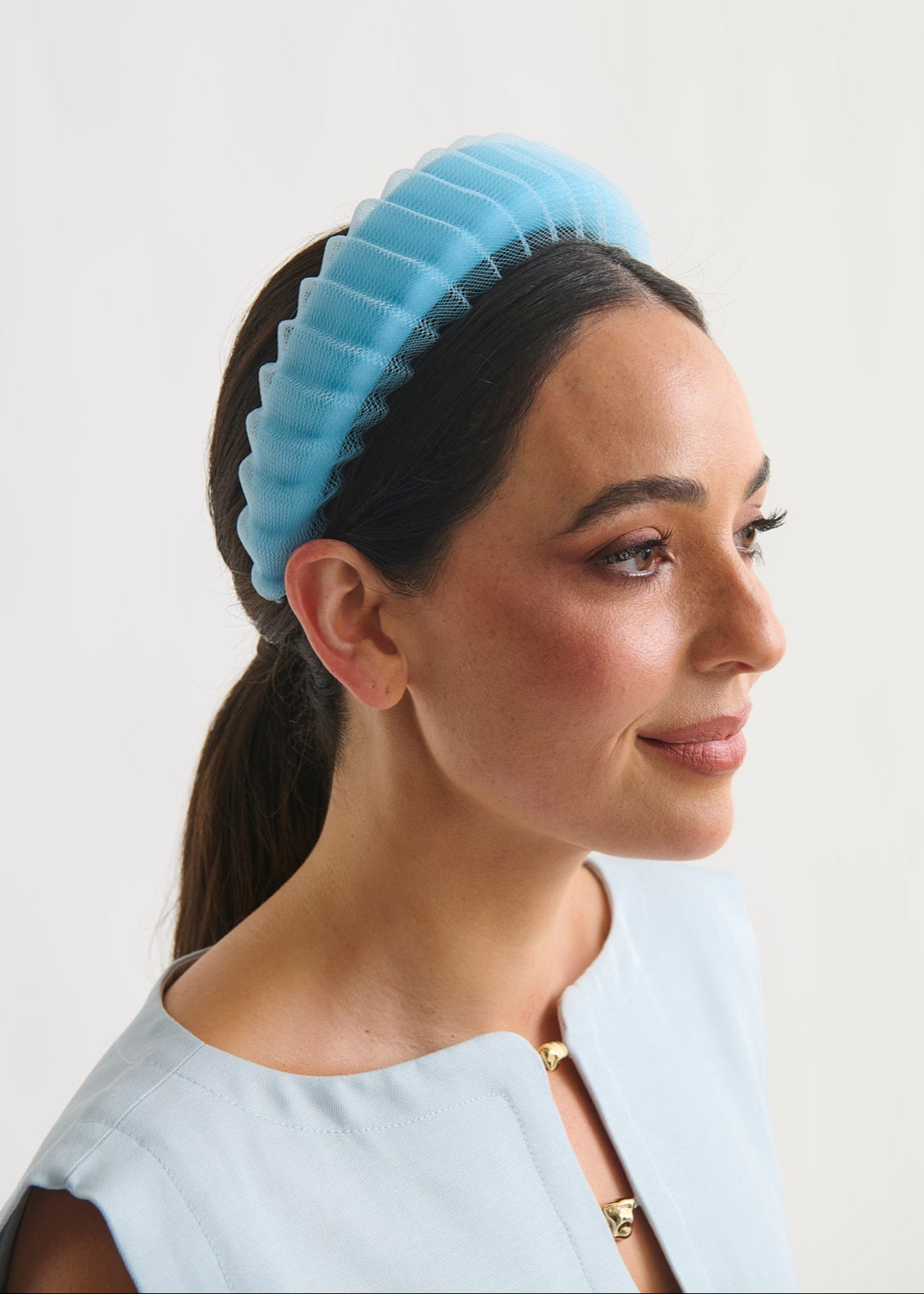 Woman wearing a blue ribbed headband against a white background