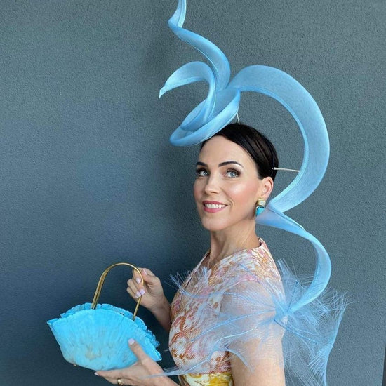Fashions on the Field entrant wearing elaborate blue designer hat holding matching handbag