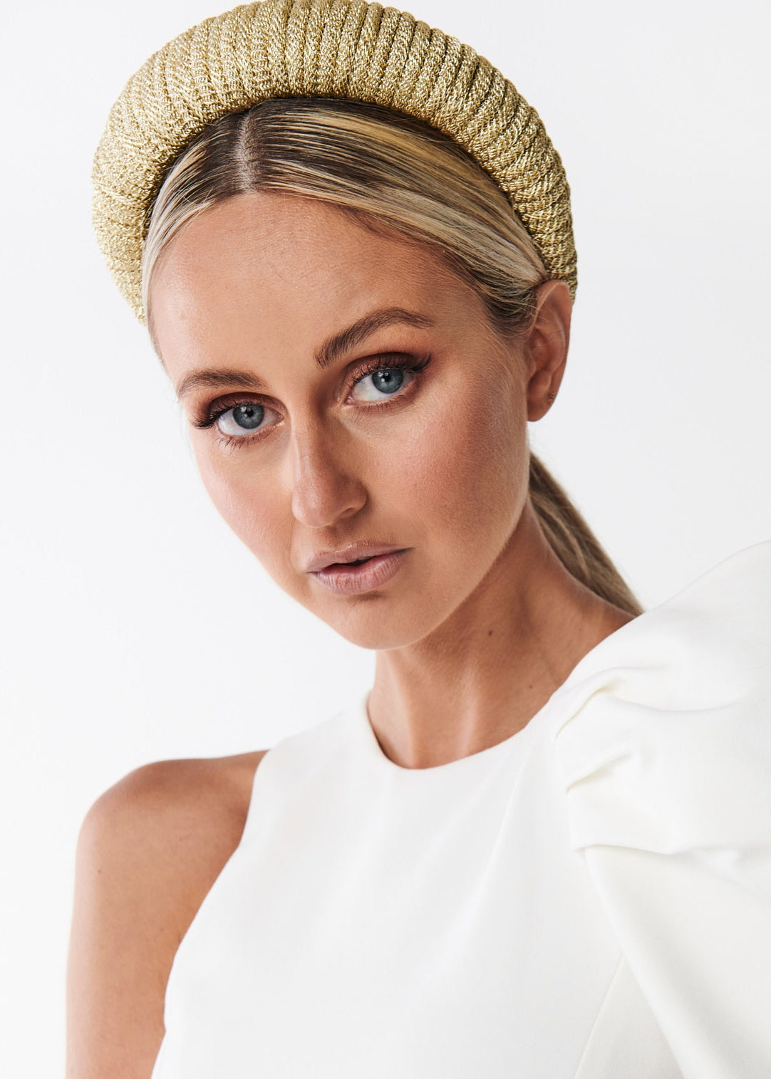 Woman wearing a white dress and gold headband on a white background