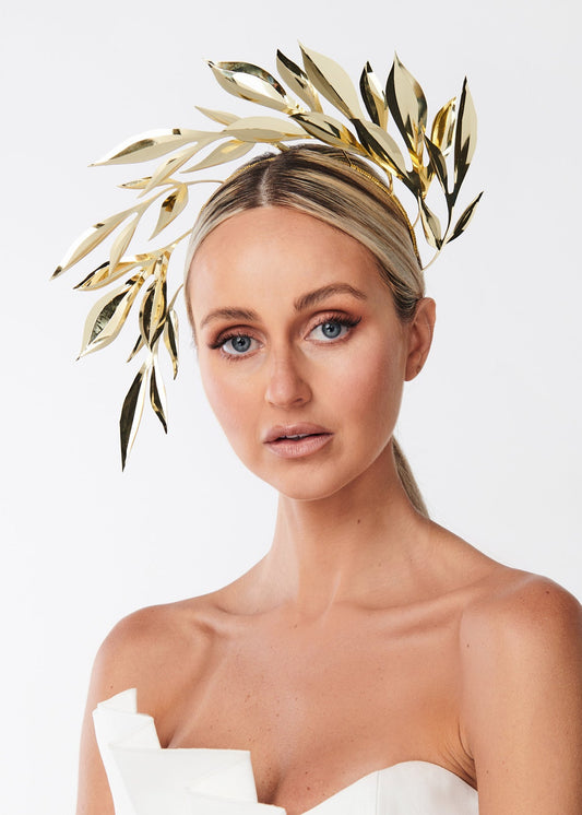 Woman wearing a gold leaf headpiece against a white background