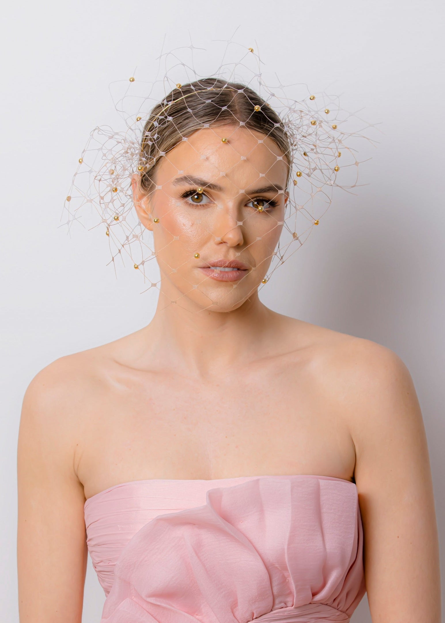 Woman wearing a strapless pink dress against a plain background