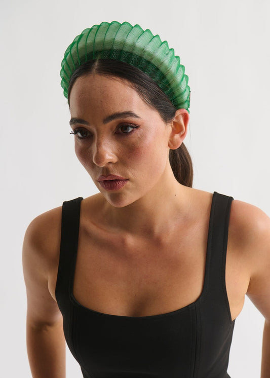 Woman wearing a green headpiece and black dress against a white background