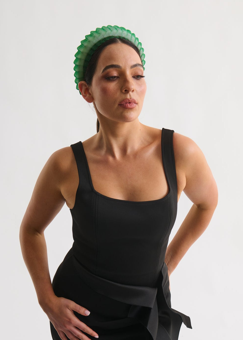 Woman wearing a black dress with a green headband against a white background