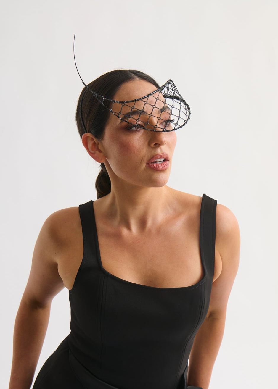 Woman wearing a black dress and netting face veil with a white background