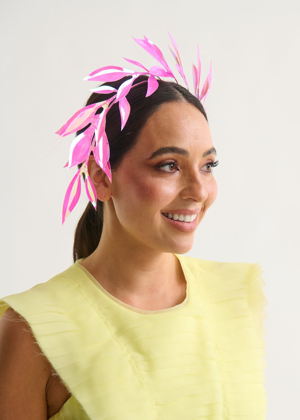 woman wearing a hot pink leaf headpiece with a white background