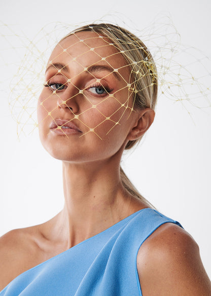 Woman with a lemon netting veil  headpiece against a white background