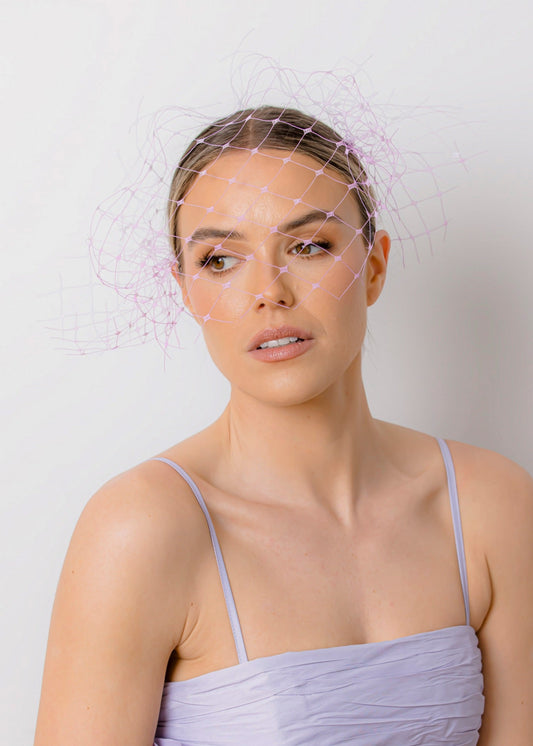 Woman wearing a light purple dress with floral details against a plain background