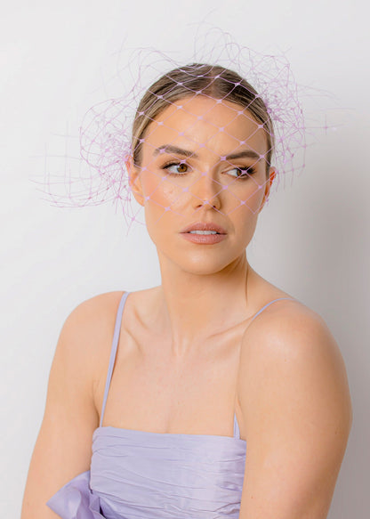 Woman wearing a light purple dress with ruffled details against a plain background
