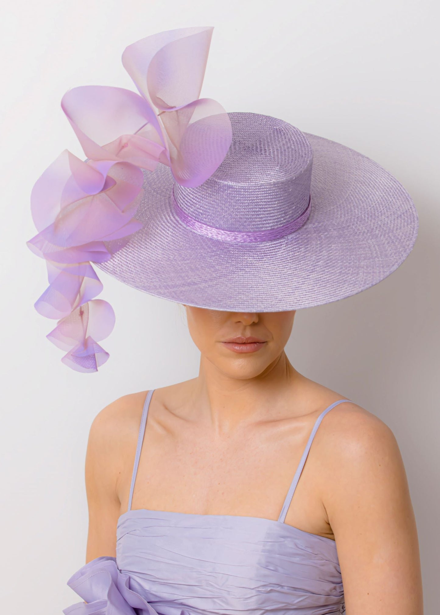 Woman wearing a lavender dress and hat with floral accents against a white background