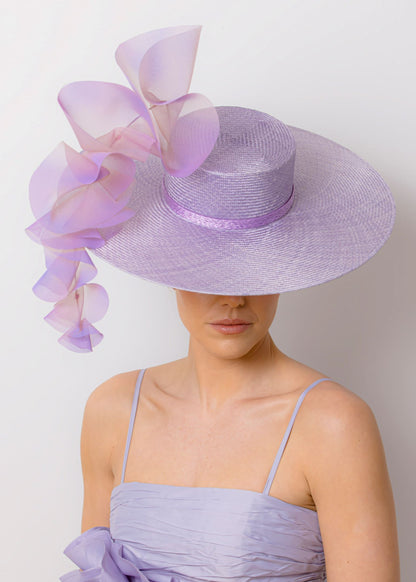 Woman wearing a lavender dress and hat with floral accents against a white background