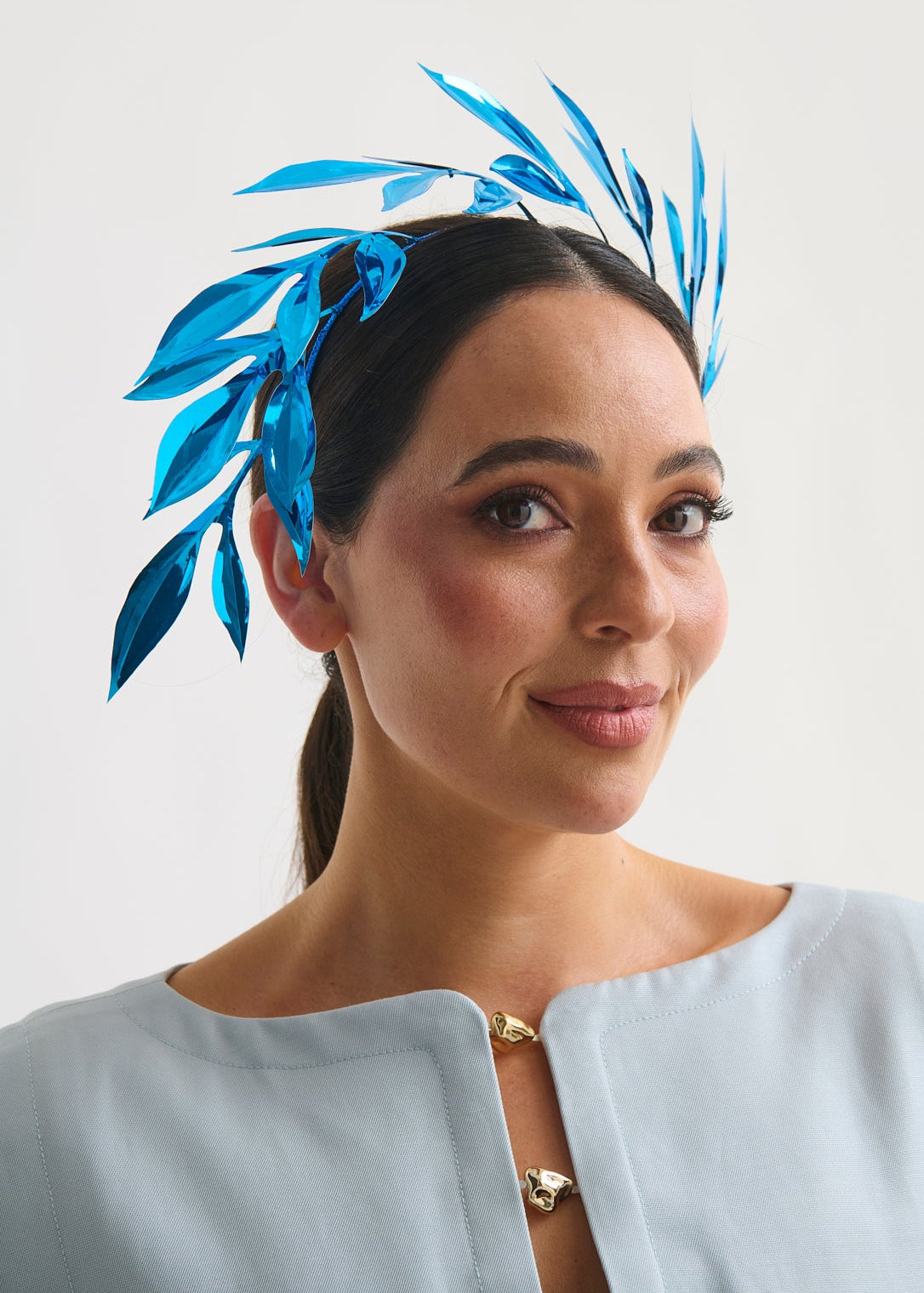 Woman wearing a blue leaf headpiece against a white background