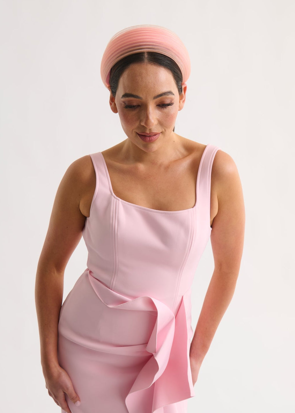 Woman wearing a pink dress and headband against a white background