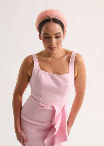 Woman wearing a pink dress and headband against a white background