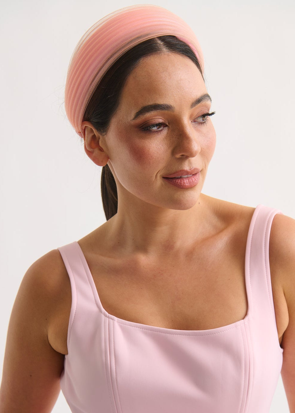Woman wearing a pink dress and headband against a white background