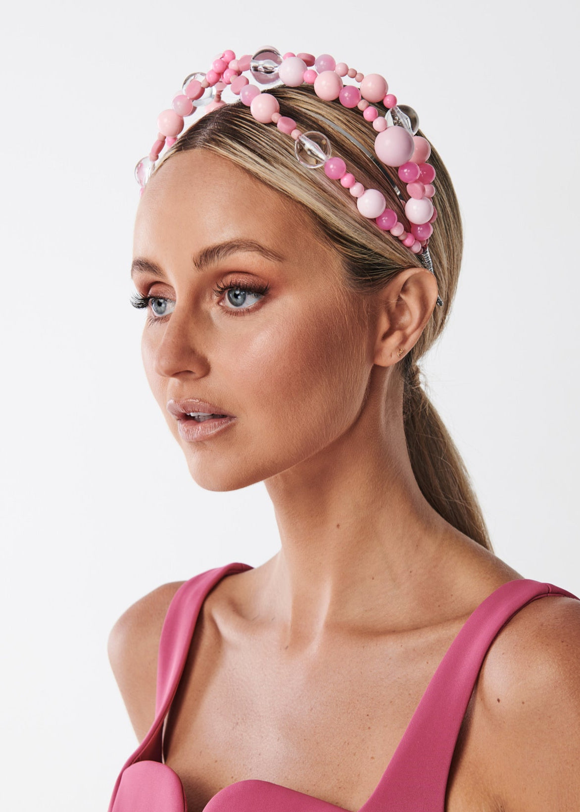 Woman wearing a pink beaded headband against a white background