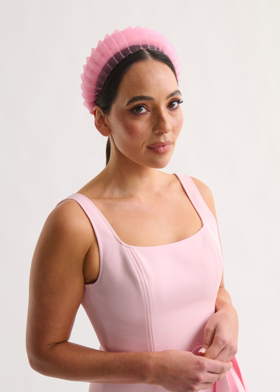 Woman wearing a pink dress and headband against a white background