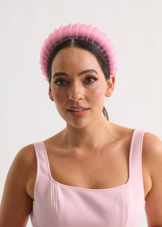 Woman wearing a pink headband against a white background
