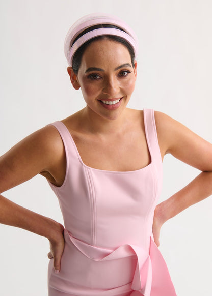 Woman wearing a pink dress and headband against a white background