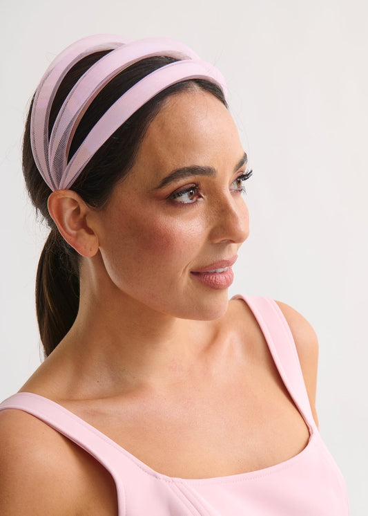 Woman wearing a pink headband and top against a white background
