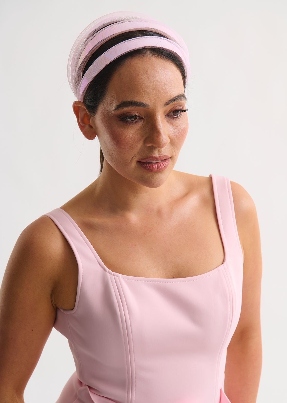 Woman wearing a pink dress and headscarf against a white background