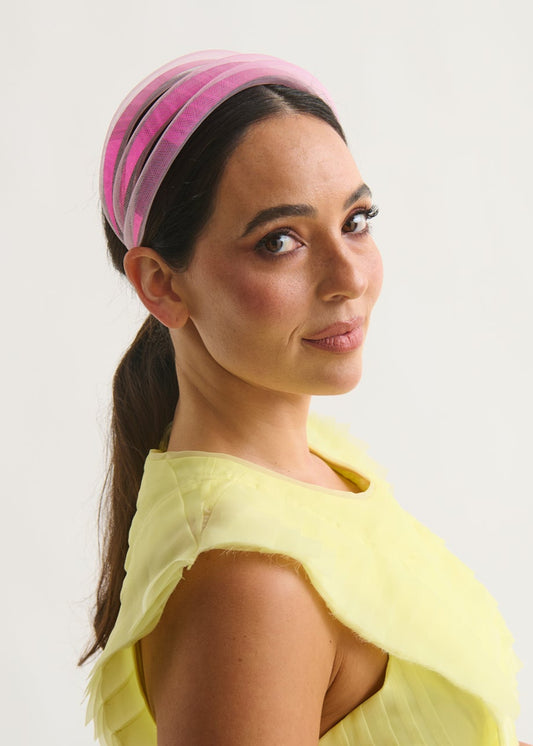 Woman wearing a pink headband and a yellow dress against a white background