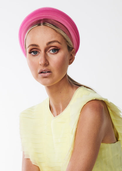 Woman wearing a bright pink headband and yellow dress on a white background