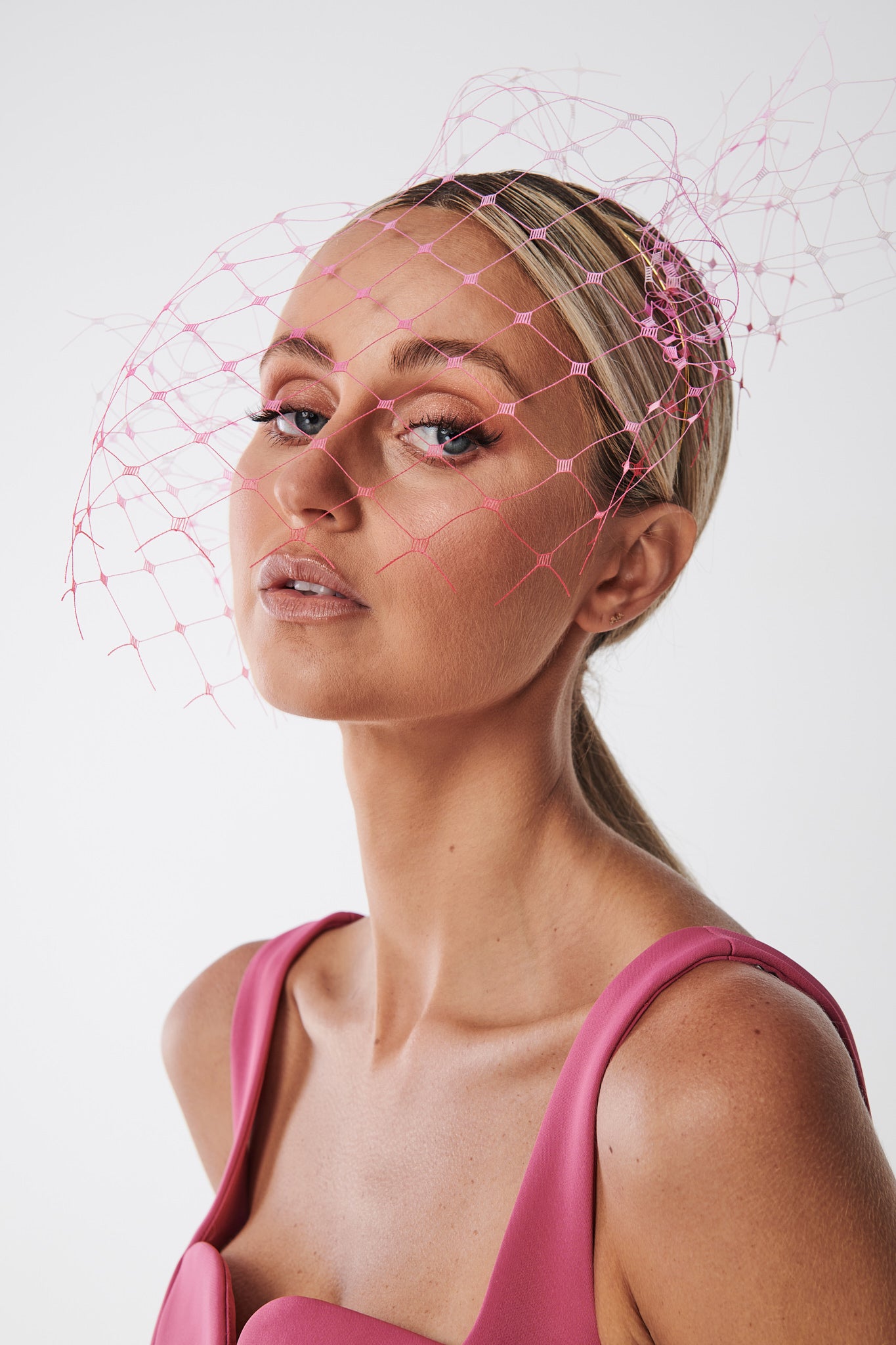 Woman with pink hair extensions and a pink top against a white background