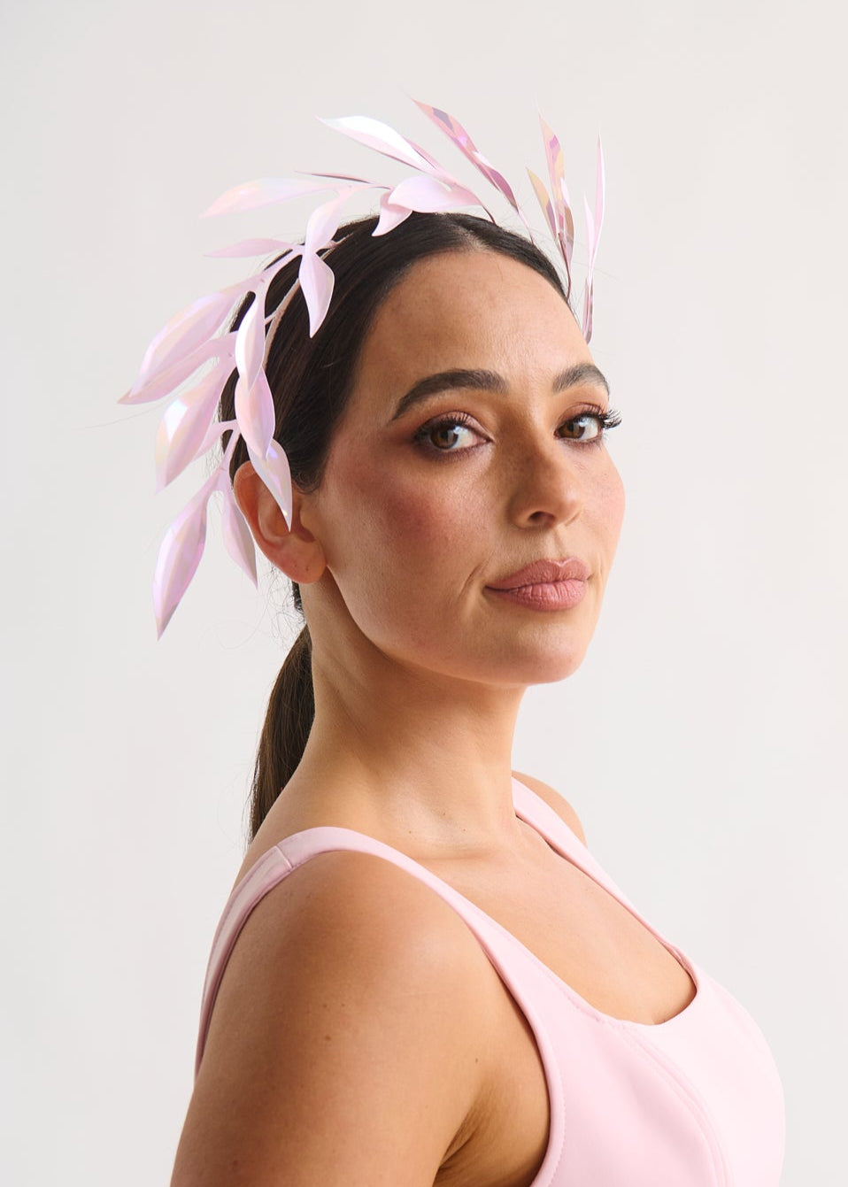 Woman wearing a pink dress and leaf headpiece against a white background