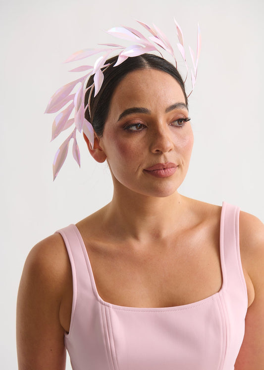 Woman wearing a pink headpiece with leaves against a white background
