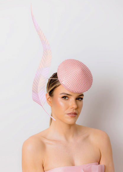Woman wearing a pink dress and hat against a white background