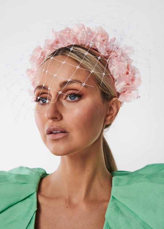 Woman wearing a pink floral headpiece against a white background