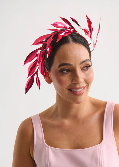Woman wearing a pink dress and red leaf headpiece on a white background