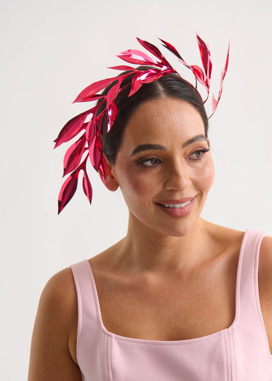 Woman wearing a pink dress and red leaf headpiece on a white background