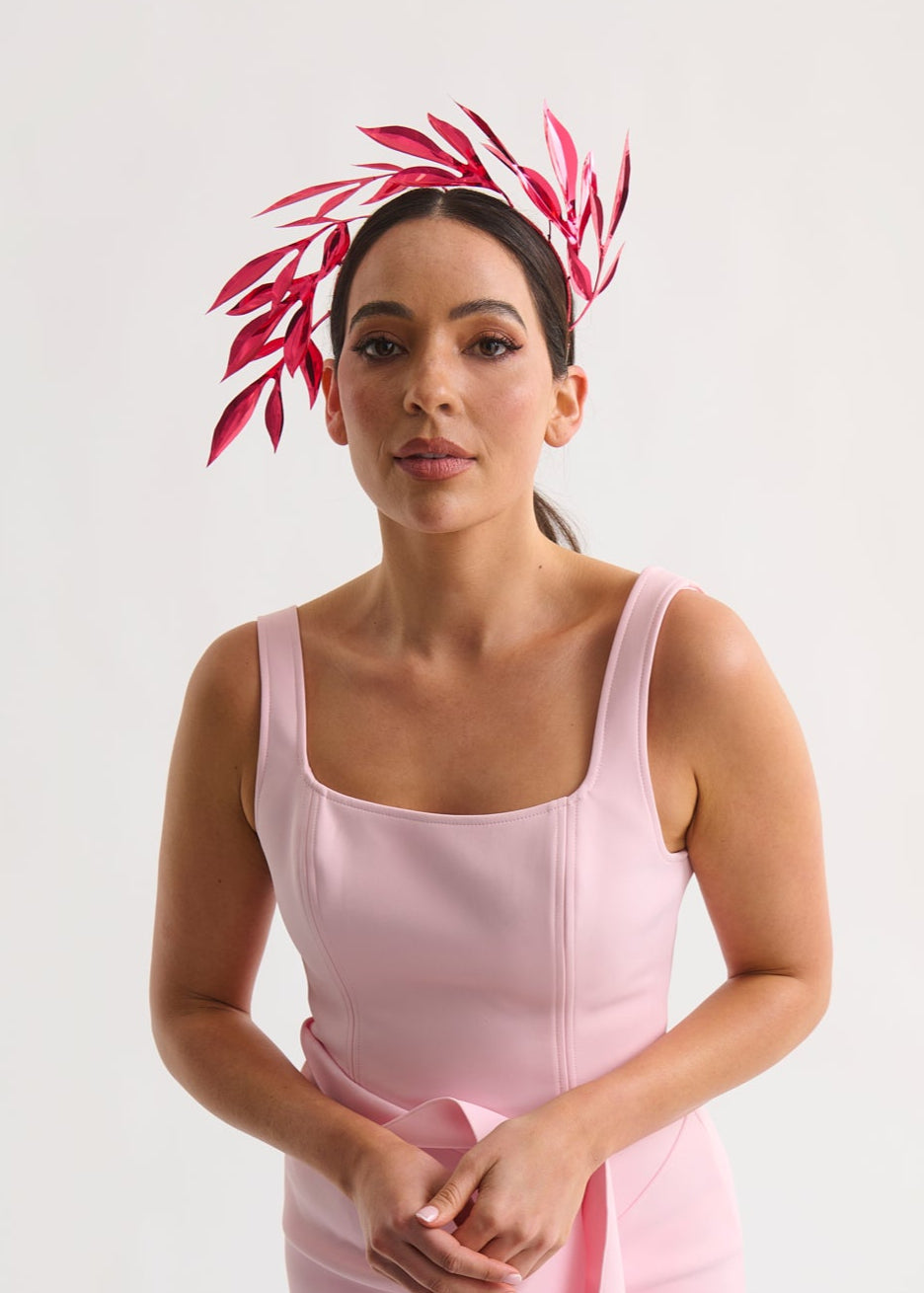 Woman wearing a pink dress with a leaf headband against a white background