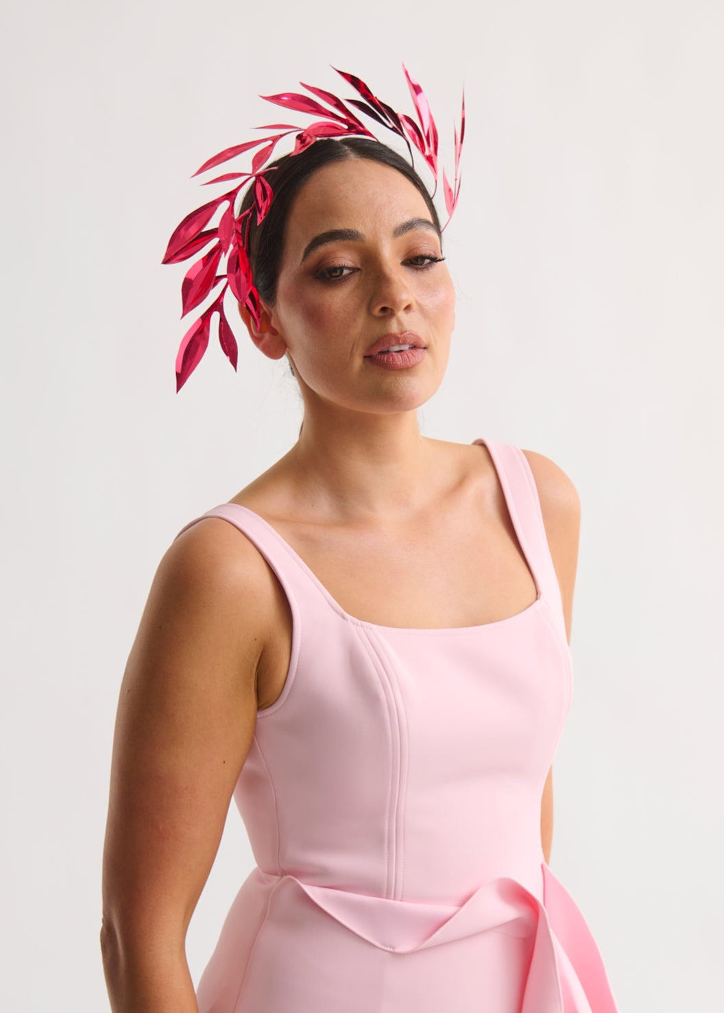 woman wearing a leaf headpiece and pink dress with a white background